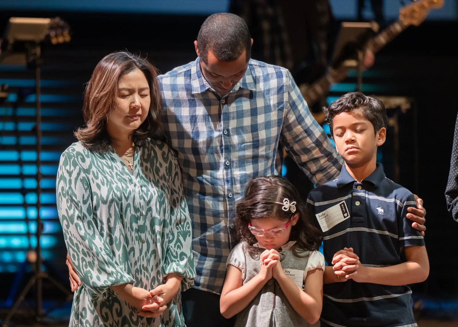 A family praying together with heads bowed during a service