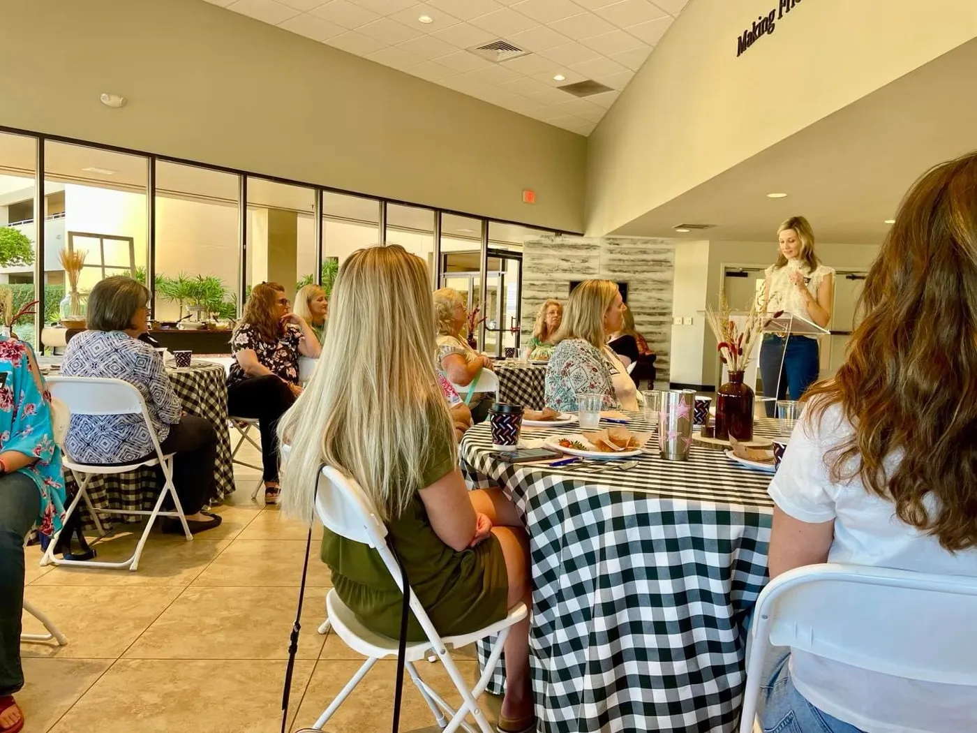 Women seated around tables at a Skycrest ladies' gathering, listening to a speaker