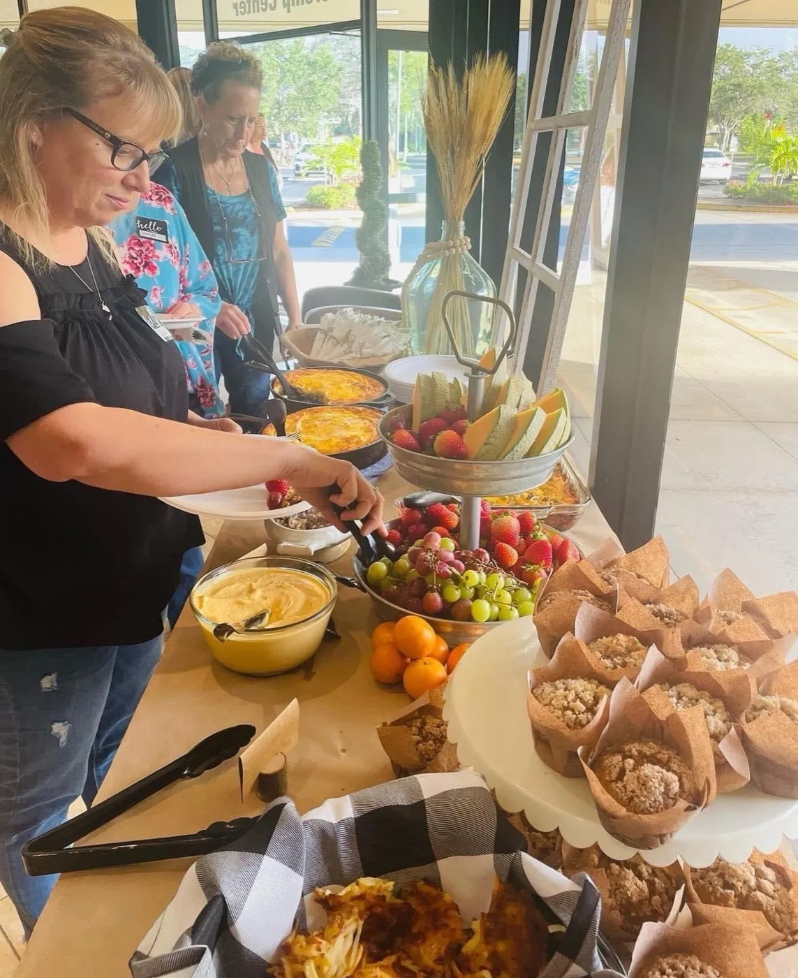 Women serving fruit, muffins and pastries from the refreshment table at a ladies' event